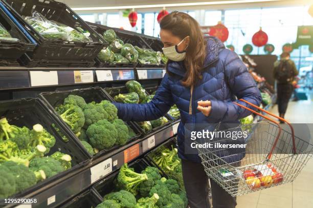 young woman shopping for healthy food in supermarket with protective facemask - protective face mask happy stock pictures, royalty-free photos & images