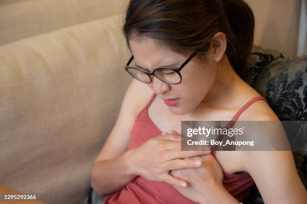 portrait of woman having suffering from chest pain or heart attack. - chest pain stock pictures, royalty-free photos & images