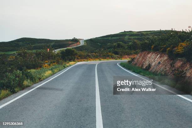 winding road though rural hills at sunset - portugal road stock pictures, royalty-free photos & images