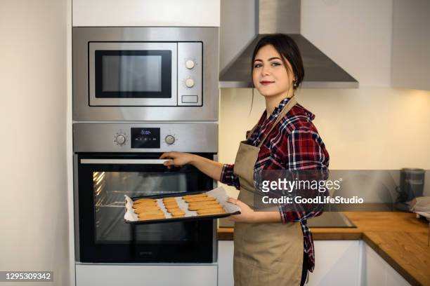 young woman baking cookies - inserting imagens e fotografias de stock