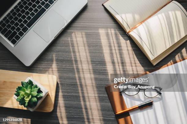 top view of objects such as notebook, computer, paper, pen, eyeglasses on the table in working office. - stationary desk stock pictures, royalty-free photos & images