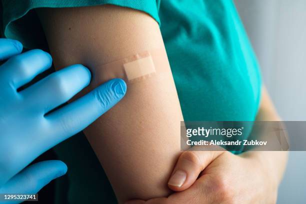 a doctor or health care professional applies a patch or adhesive bandage to a girl or young woman after vaccination or injection of medication. the concept of medicine and health care, vaccination and treatment of diseases. first aid. - vaccine bandage stock pictures, royalty-free photos & images