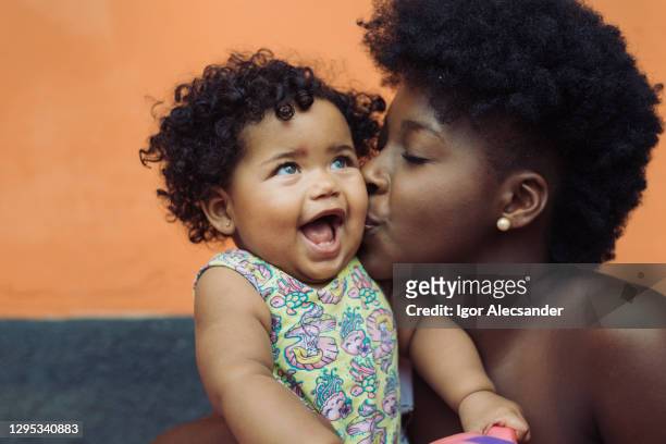 moeder die glimlachend babymeisje kust - baby stockfoto's en -beelden