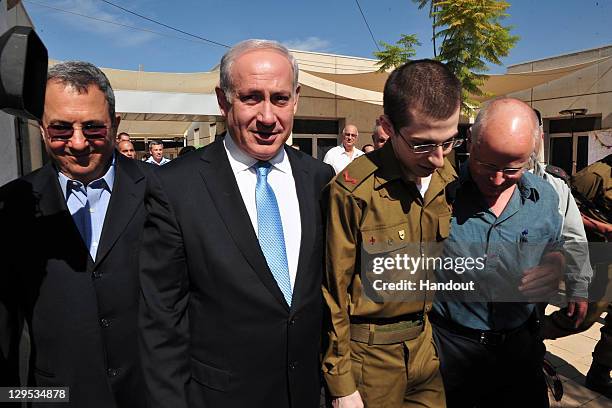 In this handout photo provided by the Israeli Defence Force, freed Israeli soldier Gilad Shalit walks with Defence Minister Ehud Barak, Israeli Prime...