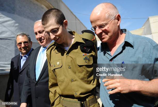 In this handout photo provided by the Israeli Defence Force, freed Israeli soldier Gilad Shalit walks with Defence Minister Ehud Barak, Israeli Prime...