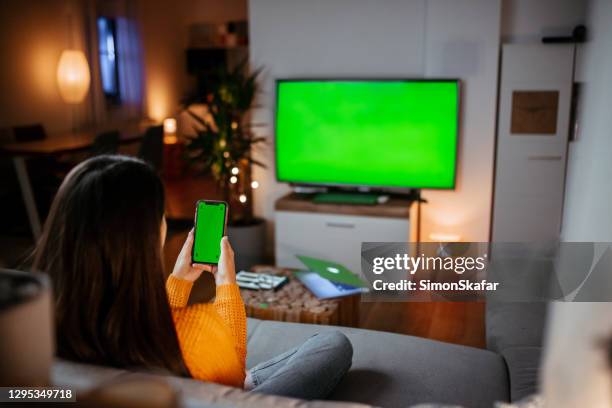woman sitting on couch with mobile phone - green screen stock pictures, royalty-free photos & images
