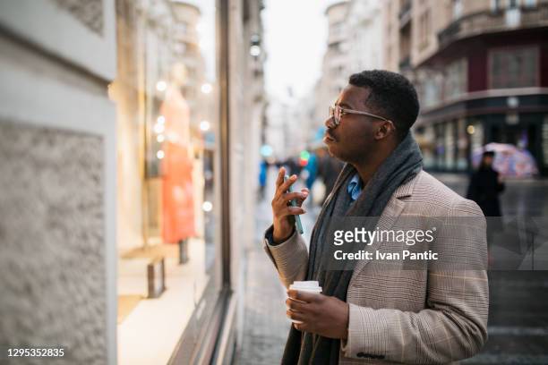 side view of a young african american man in front of a store window - consumer confidence stock pictures, royalty-free photos & images