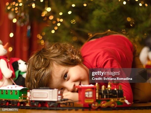 child playing toy train under the christmas tree - speelgoedtrein stockfoto's en -beelden
