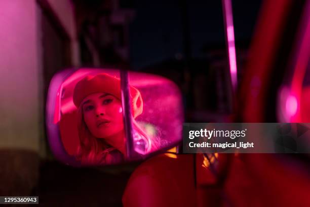 jonge vrouwennacht die in de autospiegel kijkt - cool cars stockfoto's en -beelden