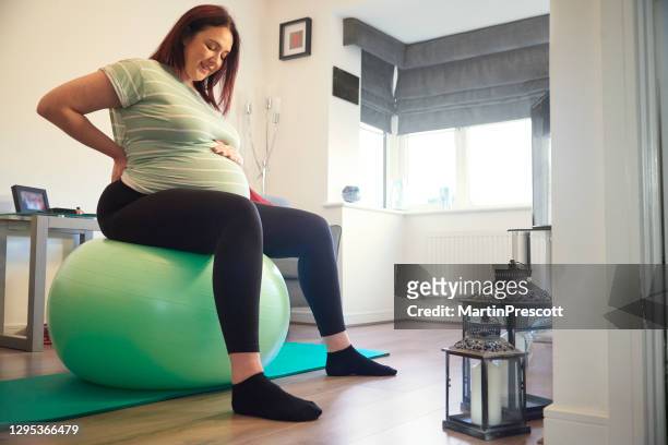 sonriendo mujer embarazada en la pelota del gimnasio - new sport content fotografías e imágenes de stock