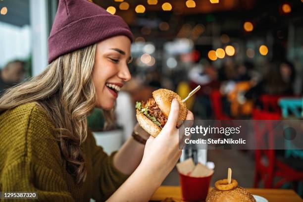 tastes like heaven - woman eating burger stock pictures, royalty-free photos & images