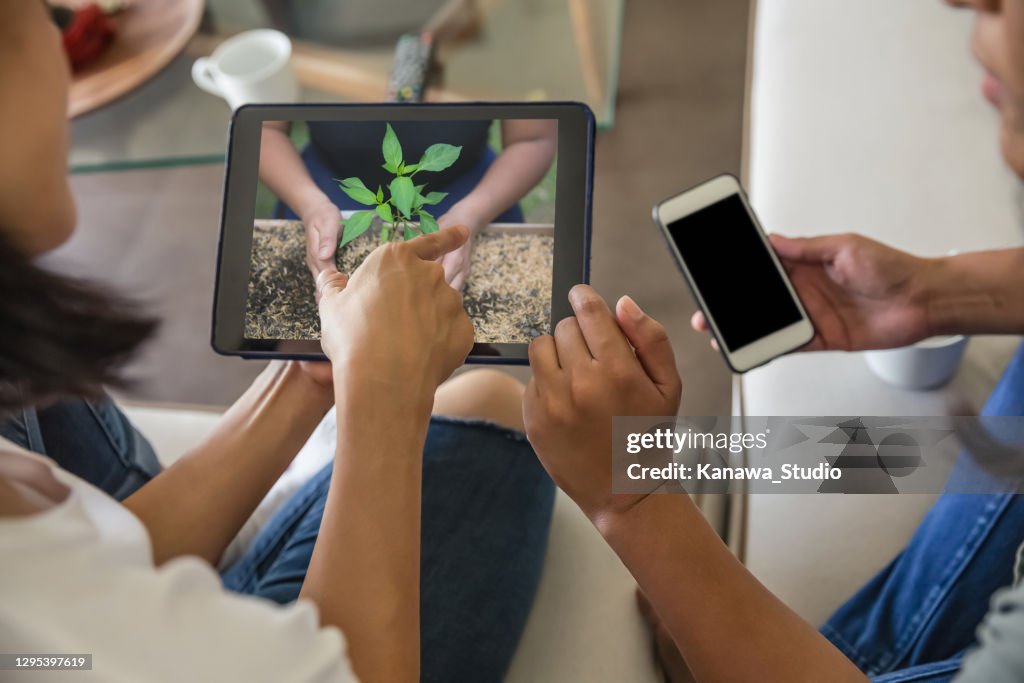 Two female friends watching online gardening tutorial from digital tablet