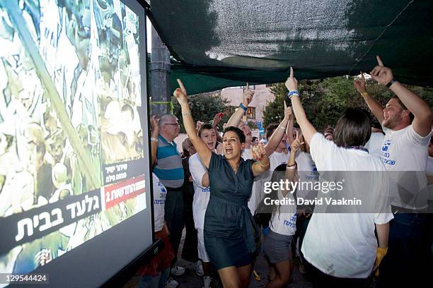 Israelis react as they watch Israeli Defense Forces soldier Gilad Shalit on television as he arrives at his hometown of Mitzpe Hila Israel, outside a...