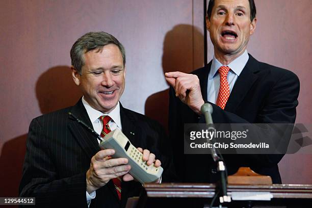 Sen. Mark Kirk holds a Motorola cell phone from the 1980s during a news conference with U.S. Sen. Ron Wyden about the 25th anniversary of the...