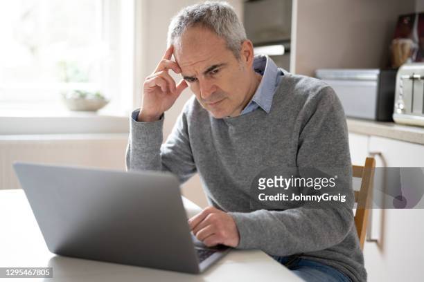 kaukasische mens 53 jaar, gebruikend laptopapparaat dat betrokken kijkt - 50 54 years stockfoto's en -beelden