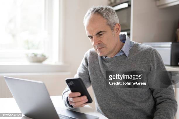 concerned mature male looking at smart phone device - candid forum stock pictures, royalty-free photos & images
