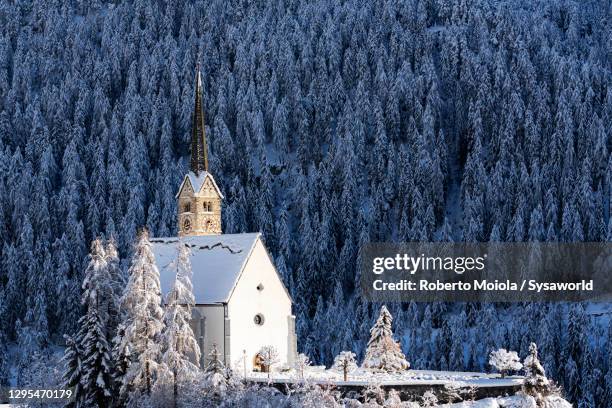 church of san geer and snowy woods, scuol, switzerland - val müstair stock-fotos und bilder