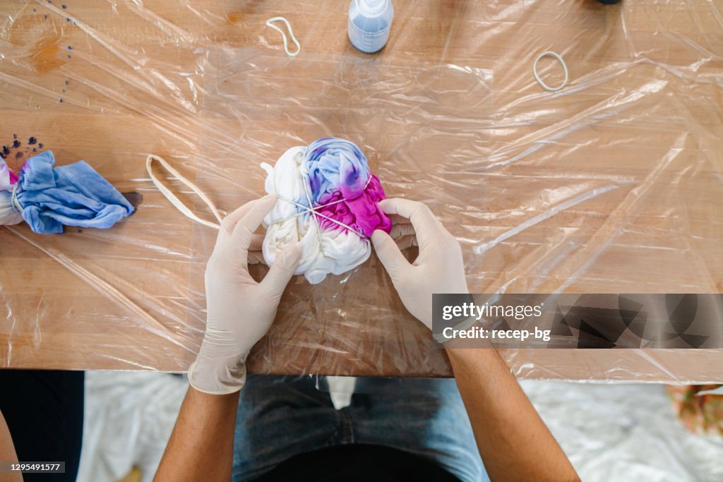 Young man making tie dye indoors