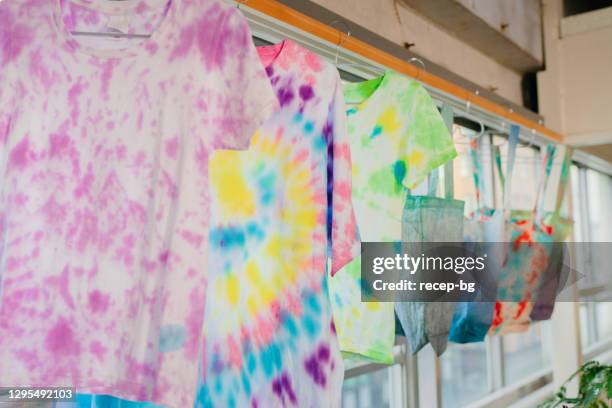 de verfoverhemden van de band en het winkelen zakken die aan droog hangen - tie dye stockfoto's en -beelden