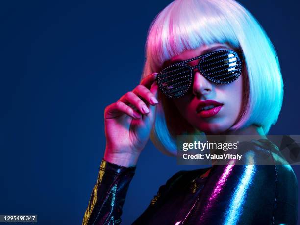 Stylish blonde in shiny dress and sunglasses with stresses. Closeup face  of beautiful  fashionable woman in white wig. Art portrait  of  an young attractive model. Fantasy style. Glamour fashion girl
