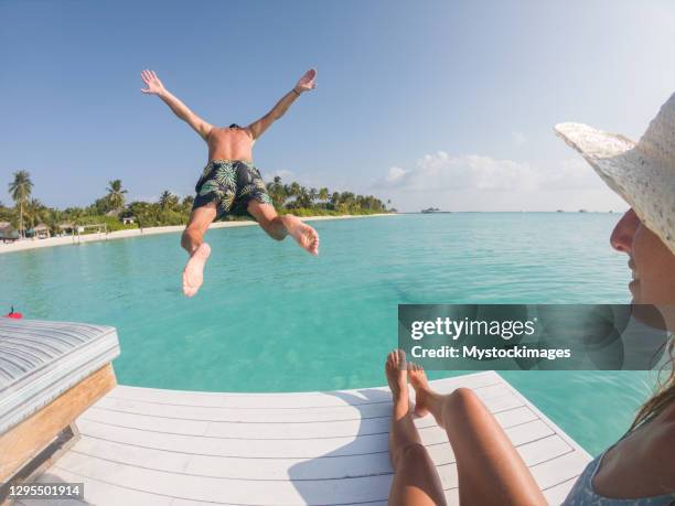 le couple apprécie des vacances de luxe, l’homme saute dans le lagon bleu - lagon photos et images de collection