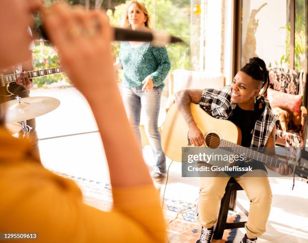 smiling guitarist jamming with her band in a home studio - jam session stock pictures, royalty-free photos & images