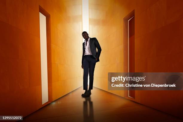 black businessman in a modern shiny corridor - circondare foto e immagini stock