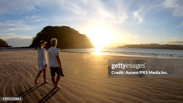 mature couple walk along beach, into sunrise - panama stock-fotos und bilder