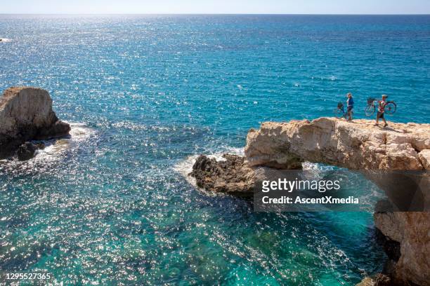 成熟的夫婦暫停與自行車在天然岩石橋，海岸線 - 塞浦路斯島 個照片及圖片檔