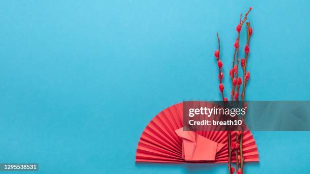 chinese new year ornament. chinese zodiac sign year of ox. red artificial plum blossom, origami paper semicircle and pig symbol of 2021 on blue background, free space for text, minimalism. - origami asia stock pictures, royalty-free photos & images