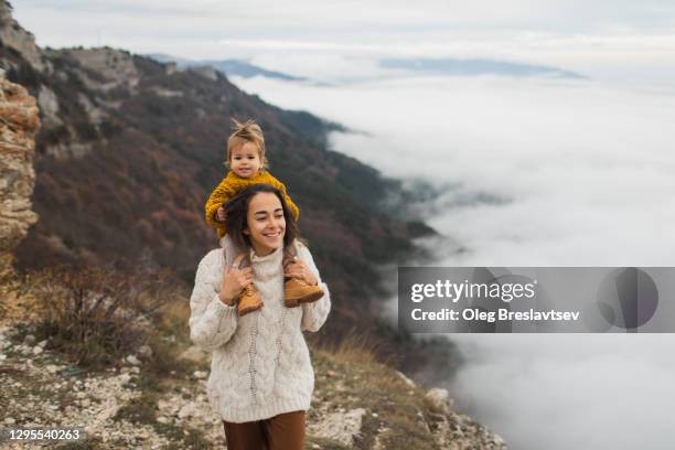 young happy woman with toddler baby daughter enjoying together. child sitting on neck. simply living and harmony with autumn nature. - baby pullover stockfoto's en -beelden
