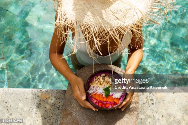 womanâs hand with smoothie bowl in swimming pool. - holiday healthy eating stock pictures, royalty-free photos & images