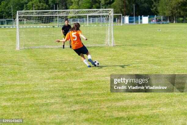 jogadora de futebol feminino pratica tiros no gol em um campo de grama - high school football - fotografias e filmes do acervo