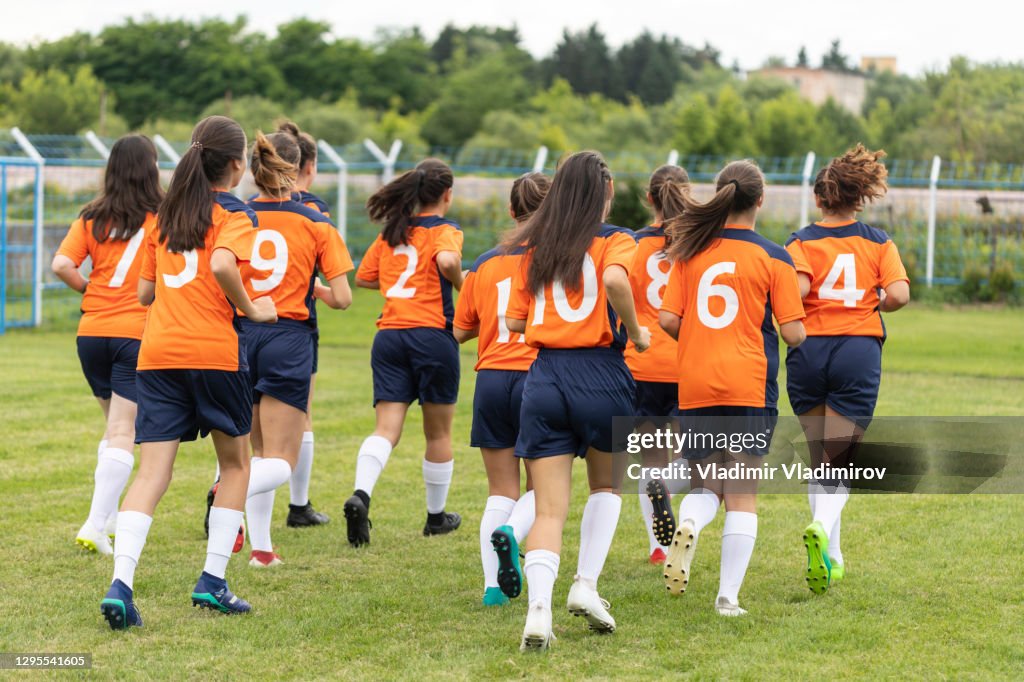 Female soccer team jogging for warming up