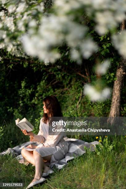 woman sitting and reading a book - mujer leyendo libro en el parque fotografías e imágenes de stock