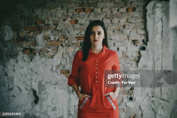 the beautiful woman against a brick wall - red dress stock pictures, royalty-free photos & images