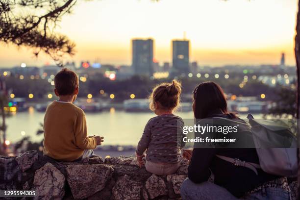 mère avec deux gosses se reposant et regardant le paysage urbain du point de vue - public building stock photos et images de collection