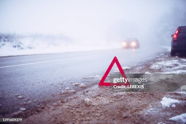 warning triangle placed on the roadway in winter conditions - slippery stock-fotos und bilder