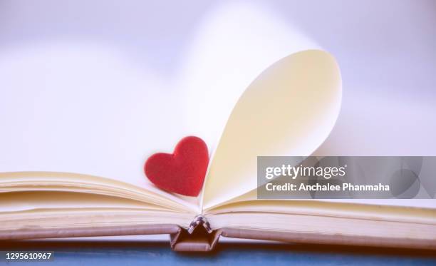 love emotion concepts: a red heart shape with blurred book background - february background stock-fotos und bilder