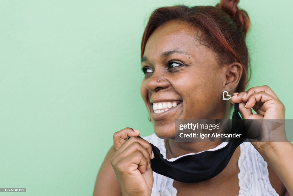 保護マスクを脱ぐ笑顔の女性