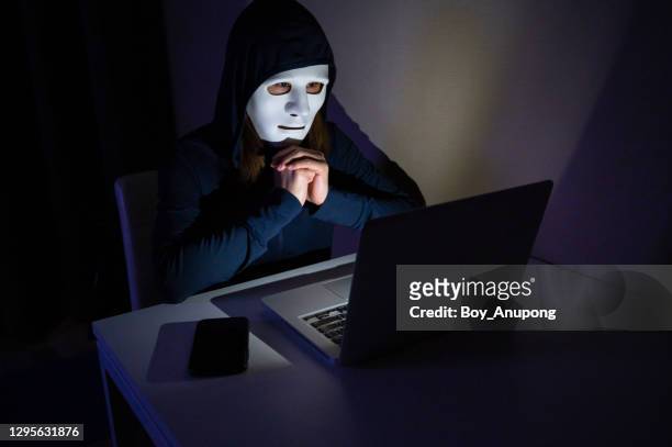 unidentified female hacker trying to hacking internet server in the dark. - acosador fotografías e imágenes de stock