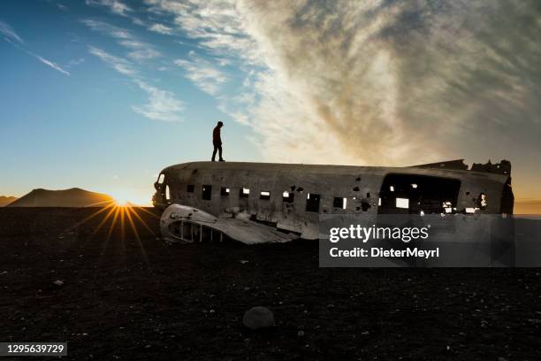 man at plane wreck on black sand beach in sólheimasandur, iceland - dakota stock pictures, royalty-free photos & images