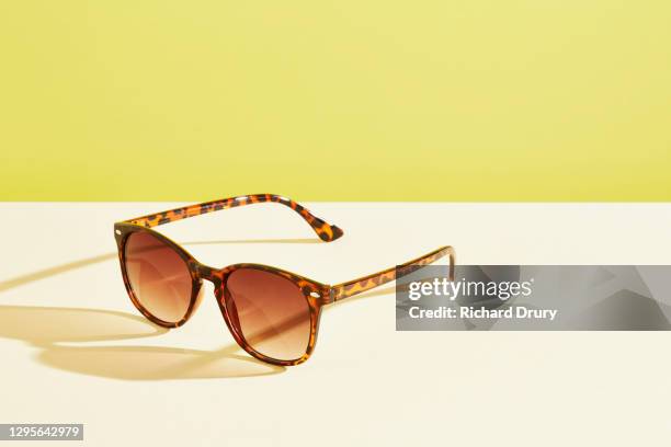 a pair of sunglasses against a yellow background - sunglasses foto e immagini stock