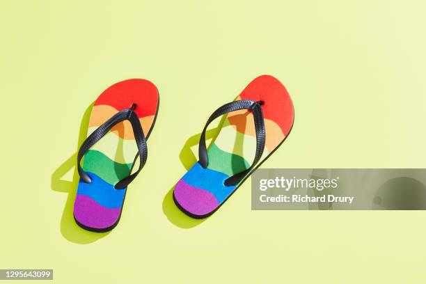 a pair of flip-flops in the design of the lgbtqi pride flag - ciabatta infradito foto e immagini stock