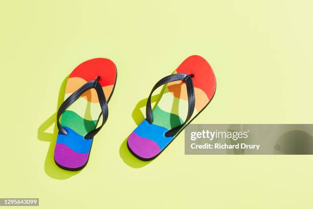 a pair of flip-flops in the design of the lgbtqi pride flag - slippers stockfoto's en -beelden