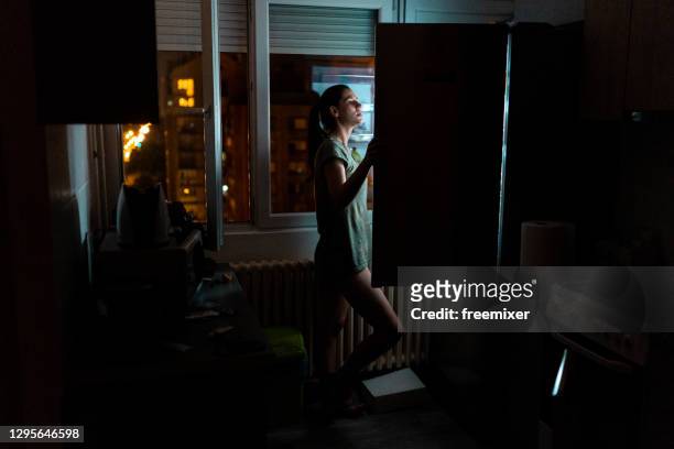 junge frau schaut nachts in den kühlschrank - refrigerator stock-fotos und bilder