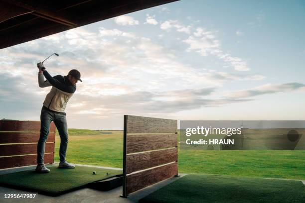 sportsman swinging golf club at course against sky - driving range stock pictures, royalty-free photos & images
