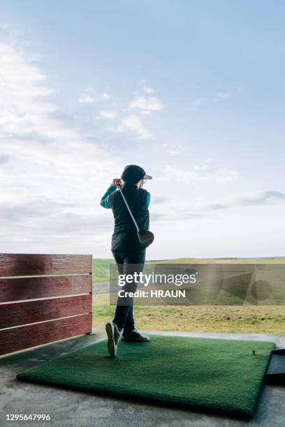 rentnerin schwingt golfschläger auf dem platz - woman swinging at golf course stock-fotos und bilder