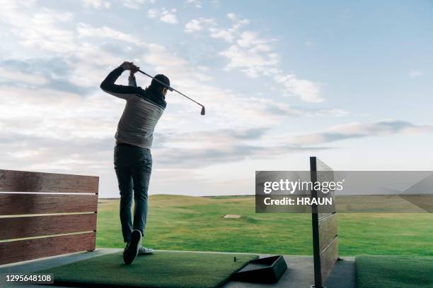 mannelijke golfer die club bij cursus tegen hemel slingert - drivingrange stockfoto's en -beelden