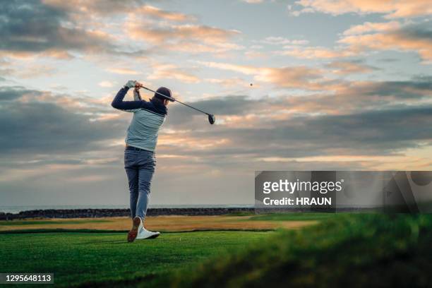 male athlete teeing off at course during sunset - golfswing stock pictures, royalty-free photos & images